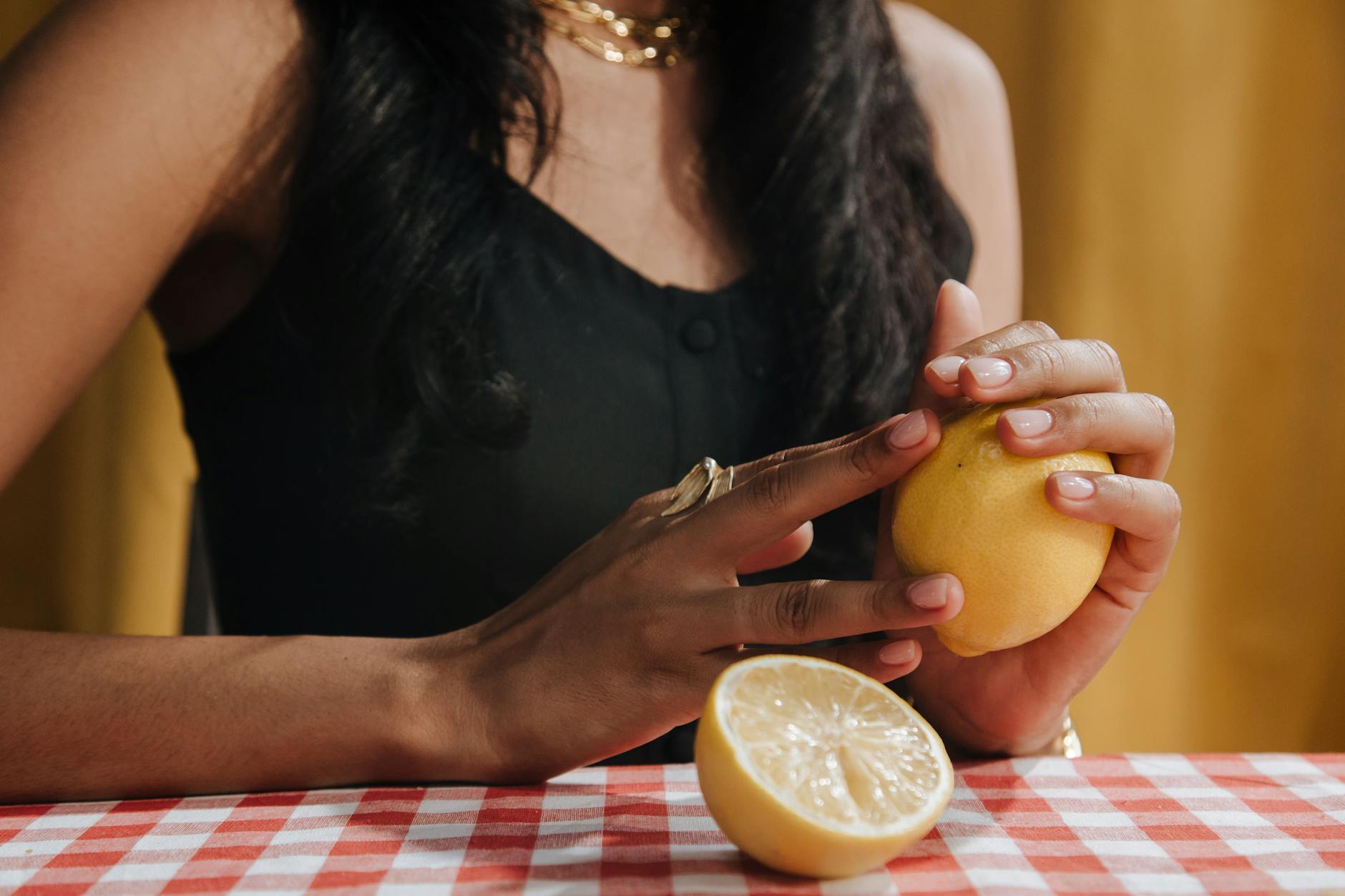 A hand holding a modern orange vibrator against a minimalistic purple backdrop