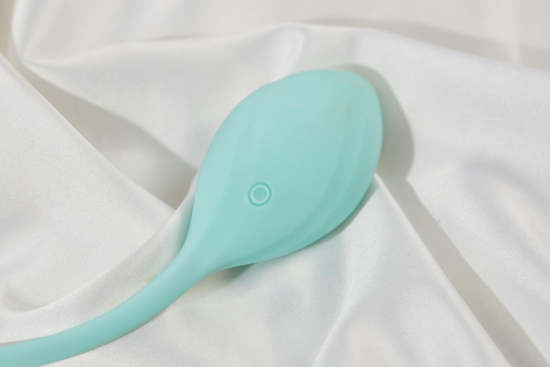 A sleek teal lemon clitoral vibrator on white silk, representing first-time toy exploration