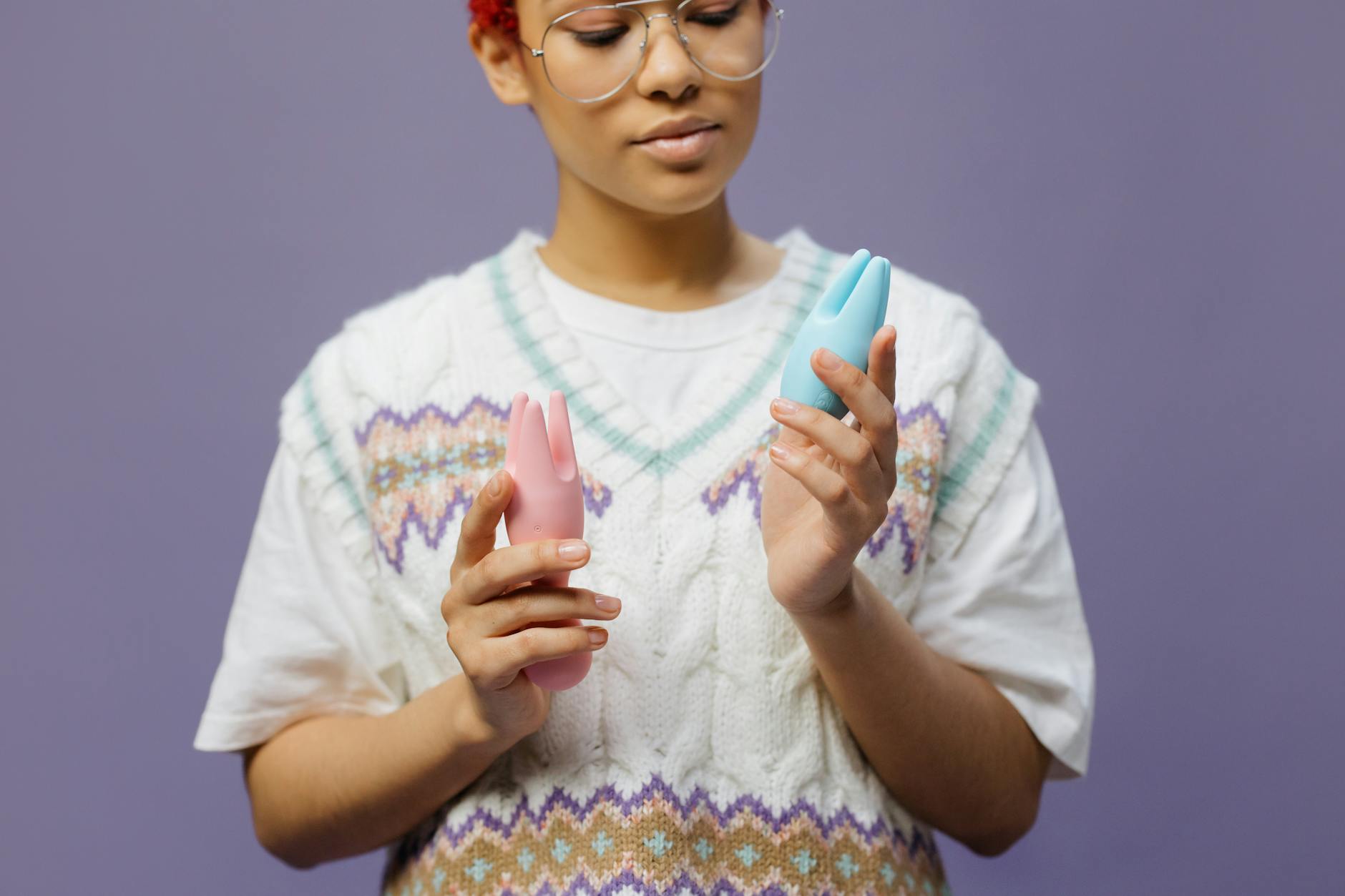 Woman holding a blue clitoral vibrator for the first time, looking thoughtful