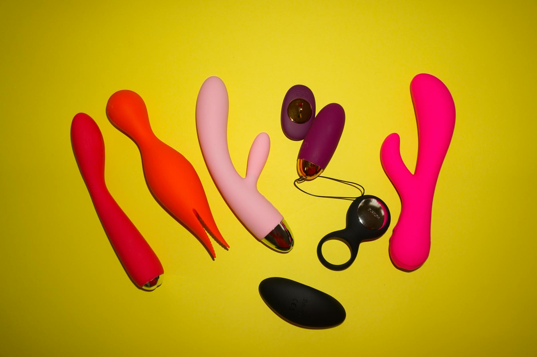 Colorful sex toys including lemon vibrators arranged on a bright yellow background